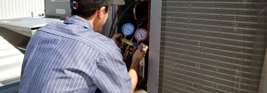 HVAC technician servicing a condenser unit in Godfrey